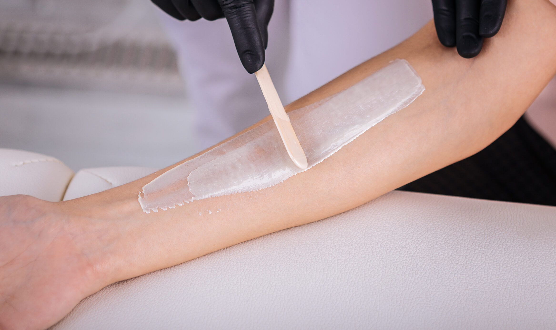 Work with client. Top view of depilatory master working hard with her client making depilation of arm